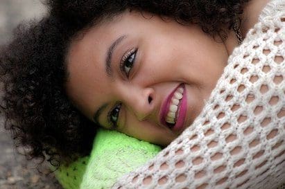 Smiling woman with curly hair and white sweater.