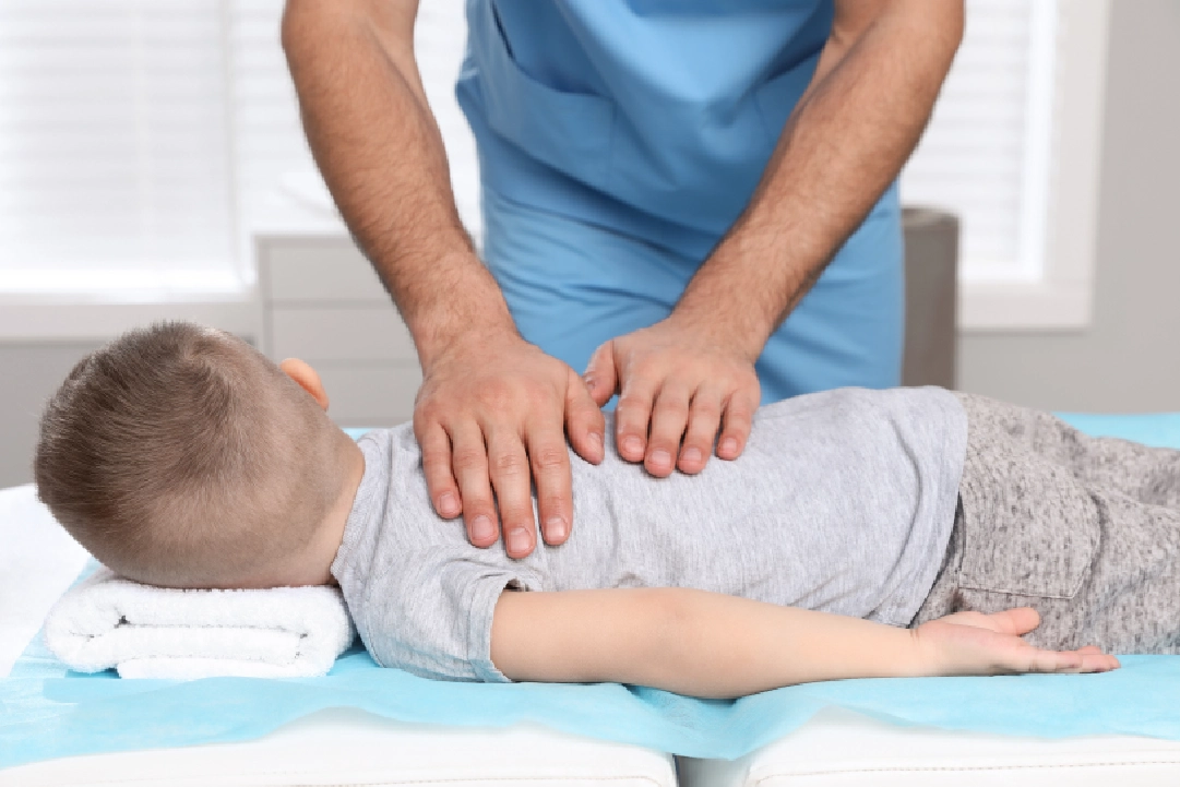 Chiropractor examining a young boy's back.