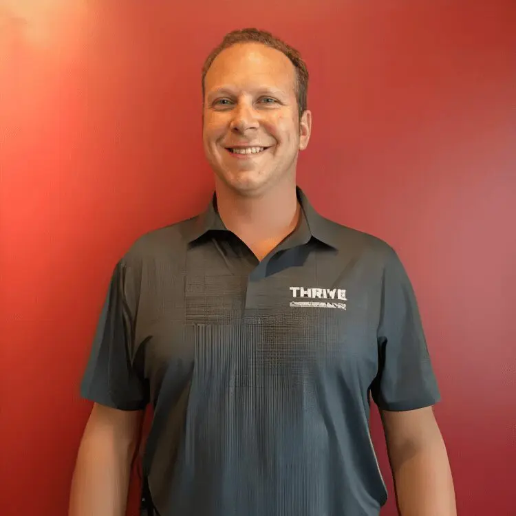 Smiling man in a gray Thrive polo shirt.