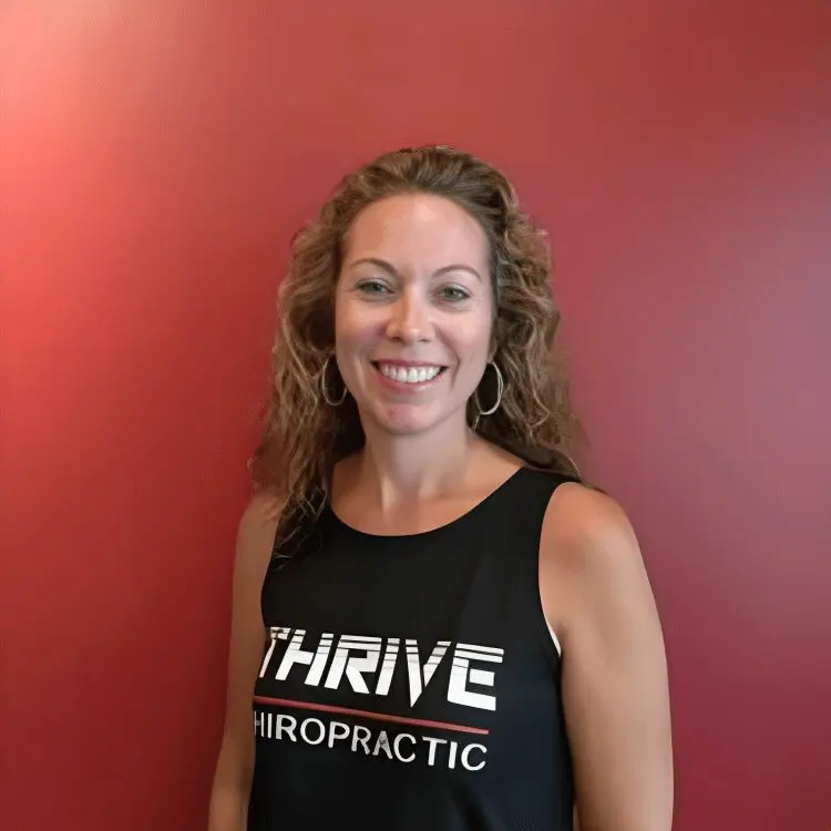 Woman smiling in black Thrive Chiropractic shirt.